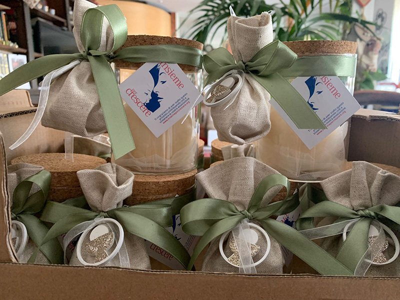 Vasetti di vetro con nastri verdi e coperture di tela, etichettati come crema naturale di olive per donazioni onlus, confezionati in una scatola di cartone. Vasetti di vetro con nastri verdi e coperture di tela, etichettati come crema naturale di olive per donazioni onlus, confezionati in una scatola di cartone.