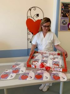 Un professionista medico sta dietro un tavolo in cui sono esposti oggetti a tema cuore in un ambiente clinico, pronto a discutere di coliche gassose con i genitori.