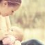 Una donna allatta un bambino all'aperto, tenendolo stretto e guardandolo dall'alto, offrendo conforto e sollievo dalle coliche gassose.